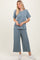 woman wearing a light blue textured v-neck top and matching wide-leg pants with white sneakers