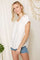 woman wearing a white short sleeve v-neck top with a chest pocket and denim shorts