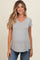 woman wearing a light gray v-neck maternity top with a baby bump and paired with blue jeans