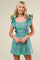 woman wearing a green and blue floral ruffled romper with a square neckline and shorts