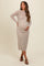 woman wearing a beige long sleeve maternity dress and holding her baby bump