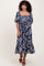 woman wearing a navy blue floral midi dress with puff sleeves and a tiered skirt