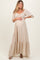 woman wearing a beige floral maternity maxi dress with puff sleeves and a gathered bust, holding her baby bump