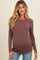 woman wearing a mauve ribbed maternity top with long sleeves and a visible baby bump