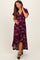 woman wearing a burgundy floral wrap maternity dress with a high-low hem and holding her baby bump