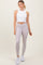 woman wearing a white cropped tank top and light gray high-waisted leggings