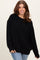 woman wearing an oversized black sweater with a ribbed hem and long sleeves, paired with blue jeans
