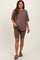 woman wearing a taupe maternity t-shirt and matching bike shorts, standing confidently and smiling