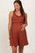 woman wearing a rust ribbed maternity dress with a ruffled waist and holding her baby bump