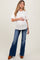 woman wearing a white short sleeve maternity top and holding her baby bump with blue flared maternity jeans