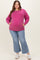 woman wearing a pink maternity plus sweatshirt with pockets and distressed light blue jeans, showcasing her baby bump
