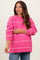 woman wearing a bright pink striped maternity sweater with long sleeves and a relaxed fit