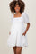woman wearing a white square neck puff sleeve maternity dress with pockets and a visible baby bump