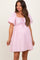 woman wearing a light pink maternity dress with puff sleeves and a drawstring detail at the waist