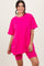 woman wearing a bright pink oversized t-shirt and matching bike shorts, smiling at the camera
