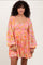 woman wearing a floral pink and orange smocked mini dress with long sleeves