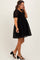 woman wearing a black maternity dress with textured floral design and puff sleeves, showing her baby bump