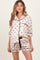 woman wearing a short sleeve maternity pajama set in cream with black bow patterns and black trim