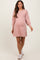 woman wearing a light pink maternity sweater dress with puff sleeves and a visible baby bump