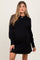 woman wearing a black long sleeve maternity dress showcasing her baby bump