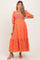 woman wearing a coral maternity midi dress with puff sleeves and floral embroidery, baby bump visible