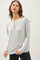 woman wearing a light gray long sleeve henley top with button details and relaxed fit