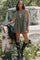woman wearing an olive green sleeveless romper with a tie detail, standing next to a vintage truck in a natural setting