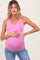 woman wearing a pink sleeveless maternity top and holding her baby bump