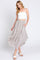 woman wearing a white cropped tank top and a flowy patterned midi skirt with pockets