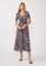 woman wearing a black floral maxi dress with short sleeves and a wrap design, standing against a white background