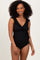 woman wearing a black ruffle-trimmed one-piece swimsuit with a wrap style and ribbed texture