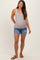 woman wearing a light gray ribbed maternity tank top and distressed denim shorts, showing her baby bump