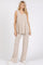 woman wearing a beige sleeveless v-neck top and matching wide-leg pants in a ribbed texture