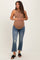 woman wearing a tan maternity tank top and distressed blue jeans, holding her baby bump
