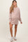 woman wearing a blush pink maternity sweatshirt dress with a visible baby bump and white sneakers