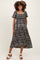 woman wearing a black and white floral print maternity dress with short puff sleeves and a square neckline