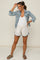woman wearing a white maternity tank top with denim jacket and cream shorts, styled with sunglasses and sandals