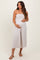 woman wearing a light beige strapless maternity jumpsuit and holding her baby bump