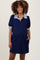 woman wearing a navy blue maternity polo dress with a striped collar and short puff sleeves, showing her baby bump