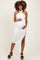 woman wearing a white ribbed maternity dress with a side slit and halter neck, gently holding her baby bump