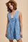 woman wearing a light blue floral sleeveless romper with a tie front detail and a straw hat