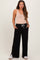 woman wearing a beige maternity bodysuit and black wide-leg maternity pants with pockets and drawstring detail