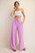 woman wearing a light gray cropped tank top and loose pink wide-leg pants with pockets