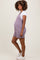 woman wearing a lavender striped maternity romper with pockets and a white t-shirt underneath, showcasing her baby bump