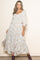 woman wearing a white floral midi dress with puff sleeves and a smocked bodice, posing against a neutral background
