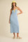 woman wearing a blue terry cloth maxi dress with yellow accents and a matching bucket hat, standing in a relaxed pose
