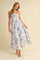woman wearing a white floral maxi dress with blue patterns and thin straps