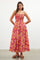 woman wearing a floral pink maxi dress with spaghetti straps and a fitted bodice, standing in a studio setting