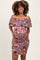 woman wearing a floral off-the-shoulder maternity dress and holding her baby bump
