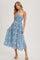 woman wearing a blue halter neck midi dress with a patterned design and a fitted bodice